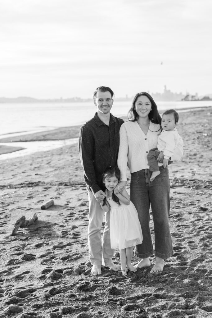 family smiles at photographer on alameda beach