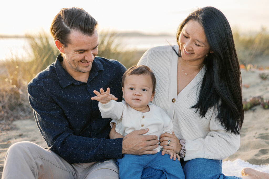 mom and dad watch baby as he waves to photographer during east bay family photography session