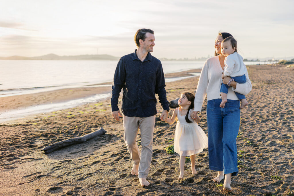 family of four with two young children walks along Bay Area Beach in alameda during family photography session