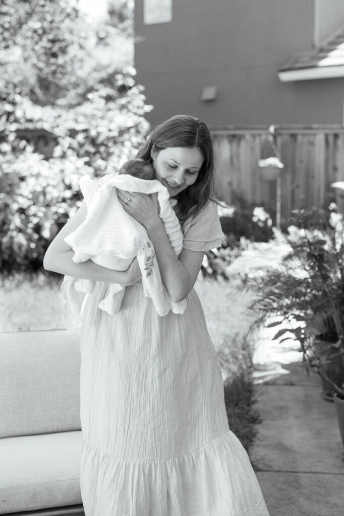 new mom picks up newborn baby and carries her outside during her in home newborn photography in San Francisco