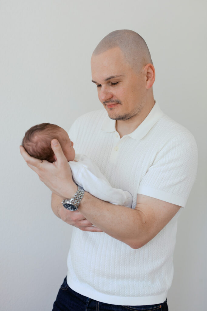 new dad looks down at his new baby during his in home newborn photography session in San Francisco