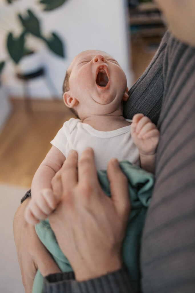 newborn baby yawns in dad's arms during an East Bay newborn photography session