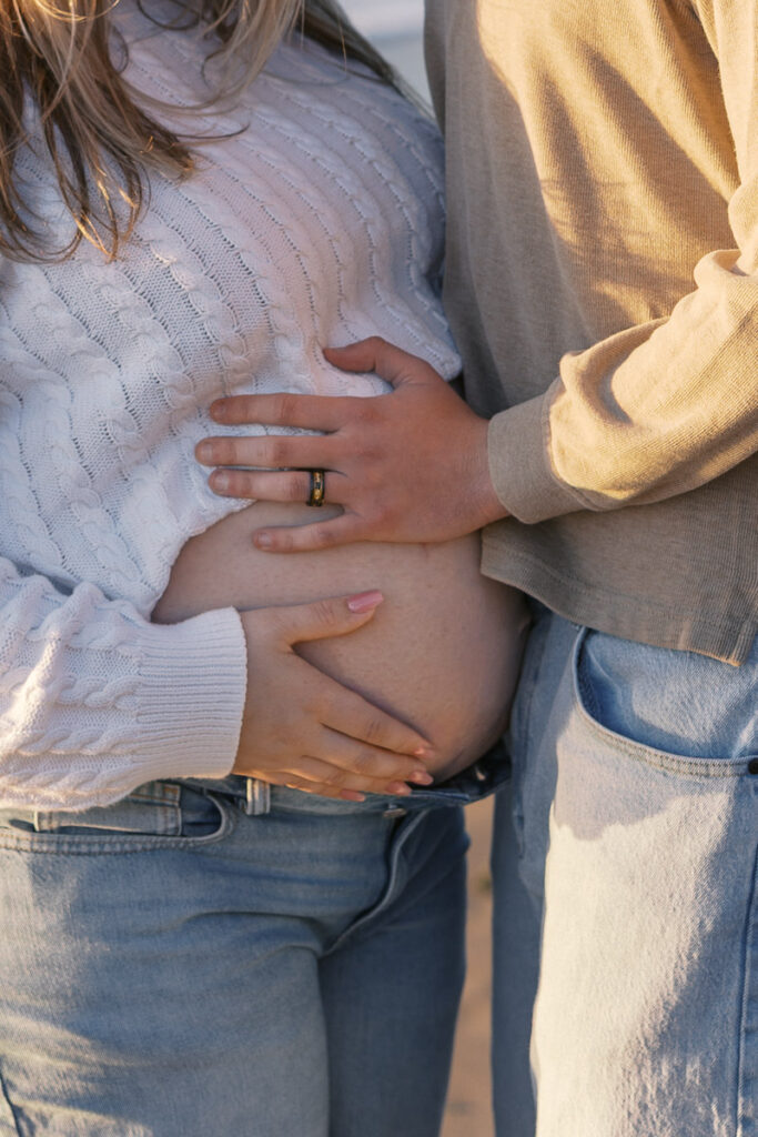 Expecting parents holding baby bump during Baker Beach maternity session