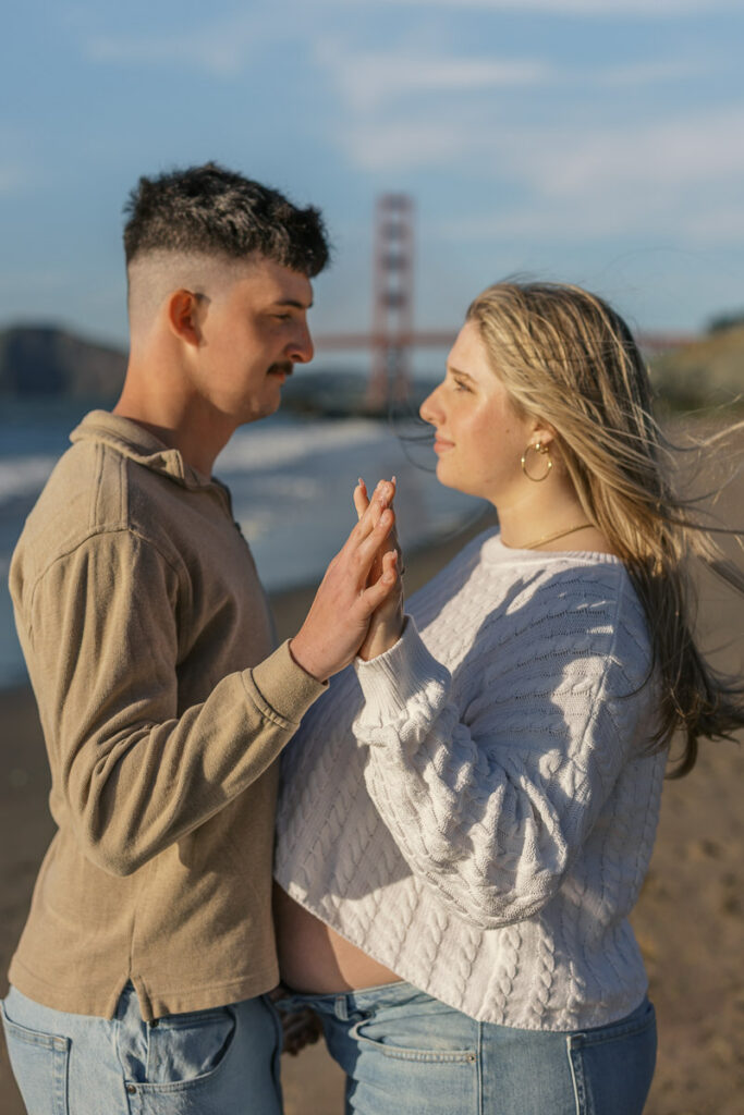 San Francisco maternity photographer capturing couple walking along Baker Beach at sunset