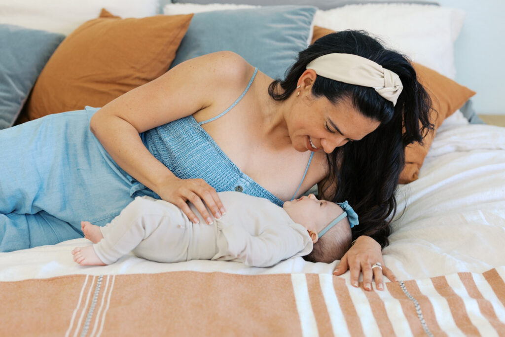 mom and 2 month old newborn cuddle on the bed with smiles during bay area newborn photography session