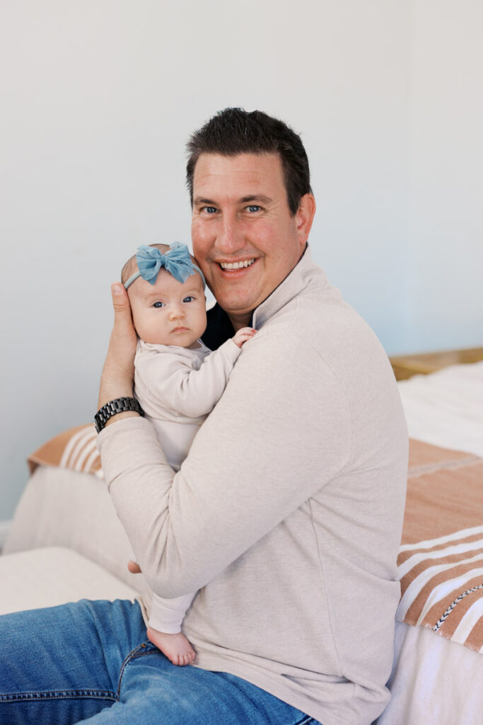 dad smiles at bay area photographer while holding 2 month old during newborn session