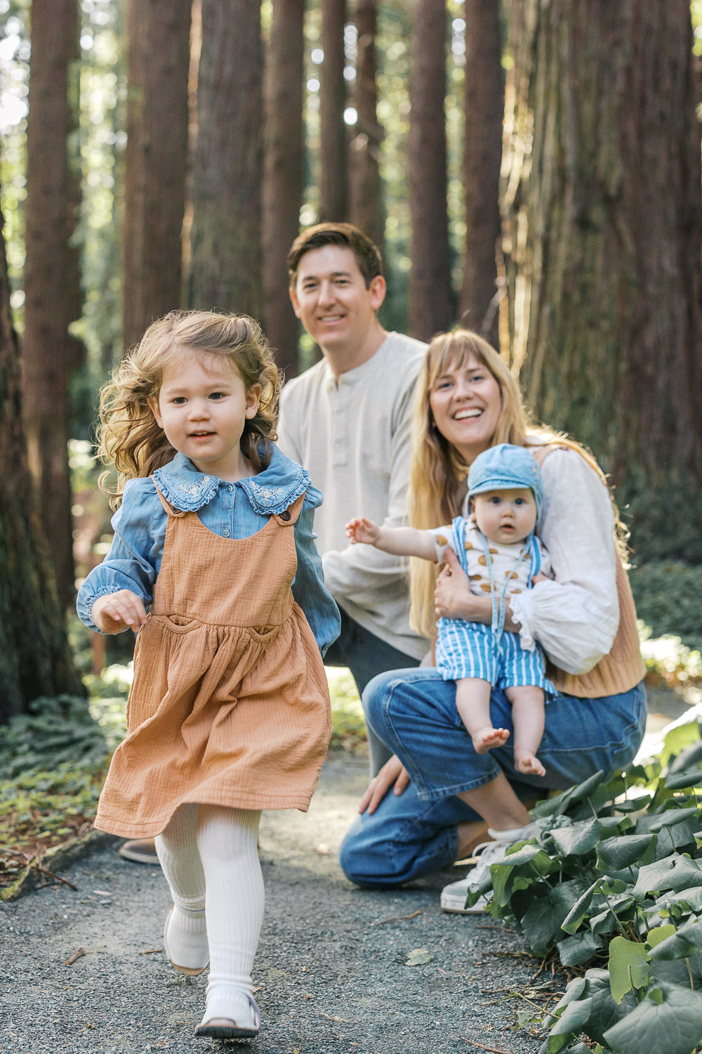young toddler runs in the redwood grove at Berkeley Botanical Garden during Berkeley family photography session