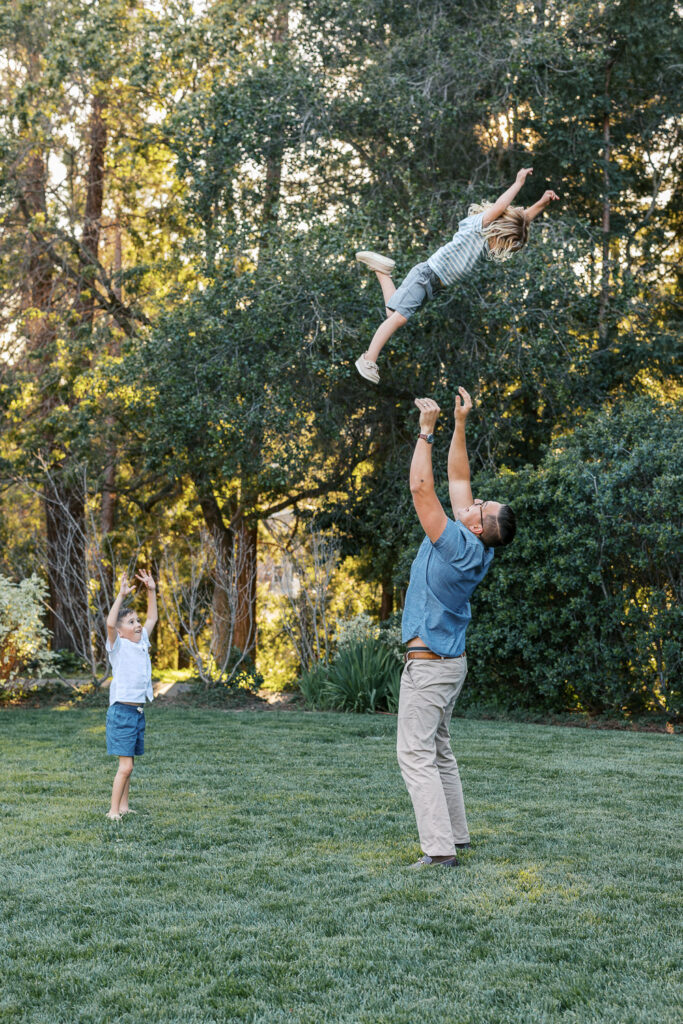 father throws young boy in the air at Dracena Park  Piedmont while brother watches