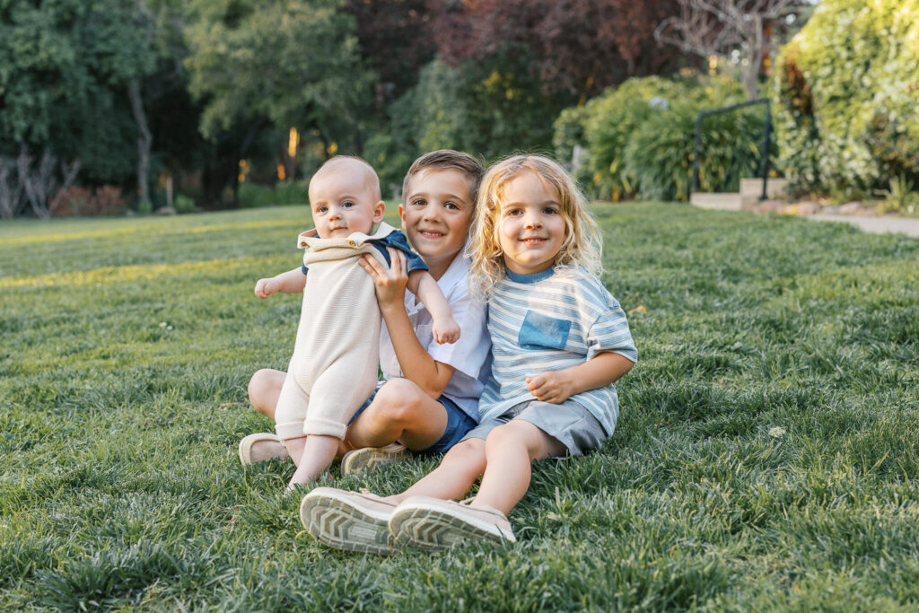 three young boys sit on grass during a piedmont family photography session at dracena park