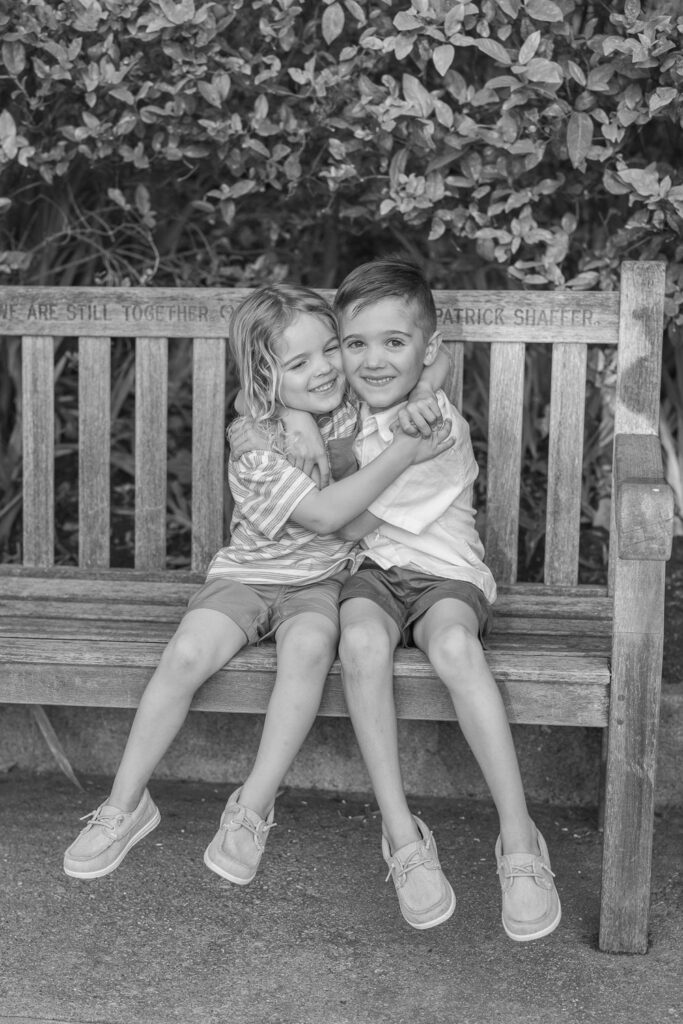two young brothers hug each other on a bench during a piedmont family photography session at dracena park