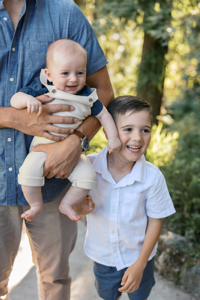 a young boy and his baby brother smile at something off camera at Dracena Park