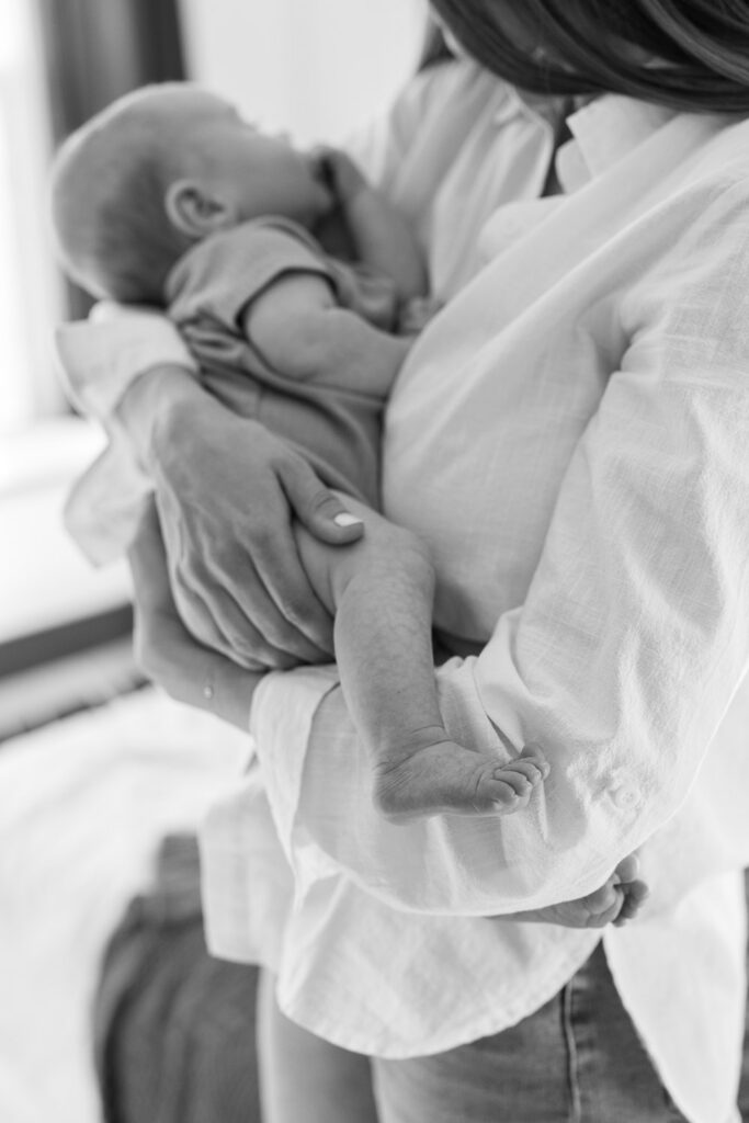 detail shot of 2 month old baby toes taken new parents hold newborn while sitting on bed with dog for San Francisco newborn photography session