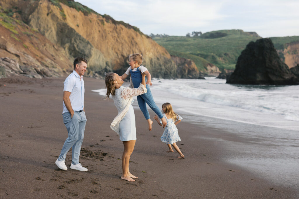 family of four plays on rodeo beach during a bay area marin county family photography session
