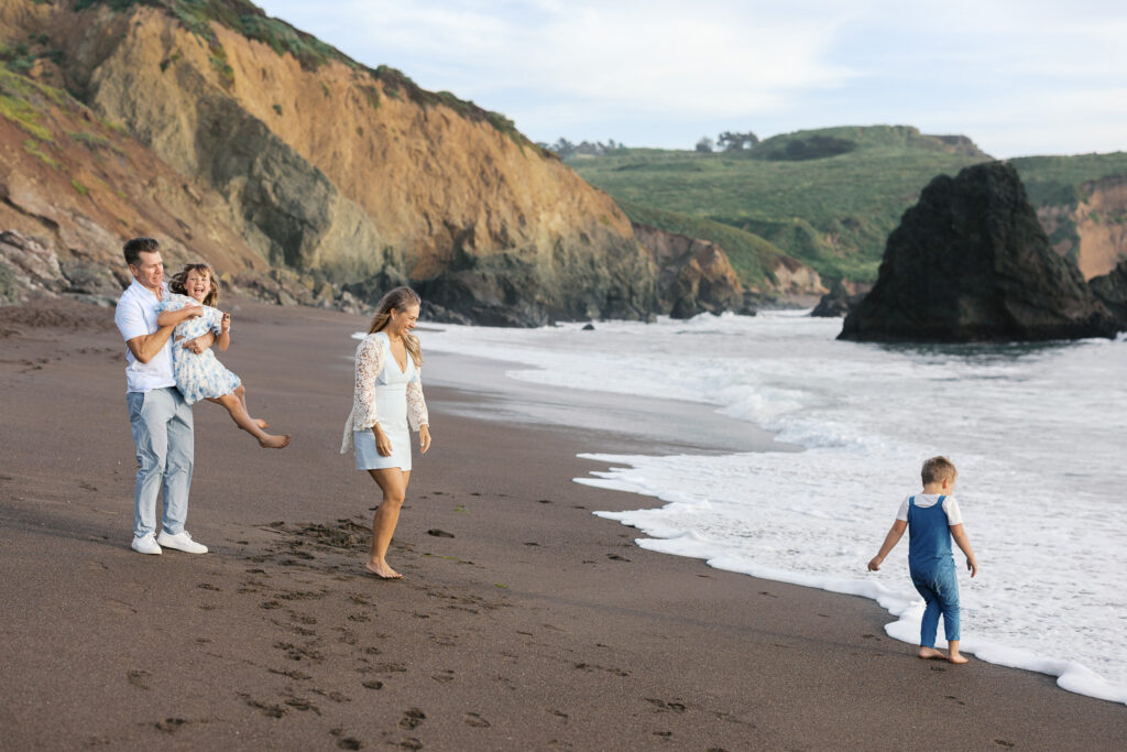 family of four plays on rodeo beach during san francisco family session in marin county