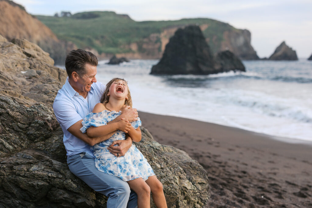 dad and daughter laugh on rodeo beach during bay area family photography session