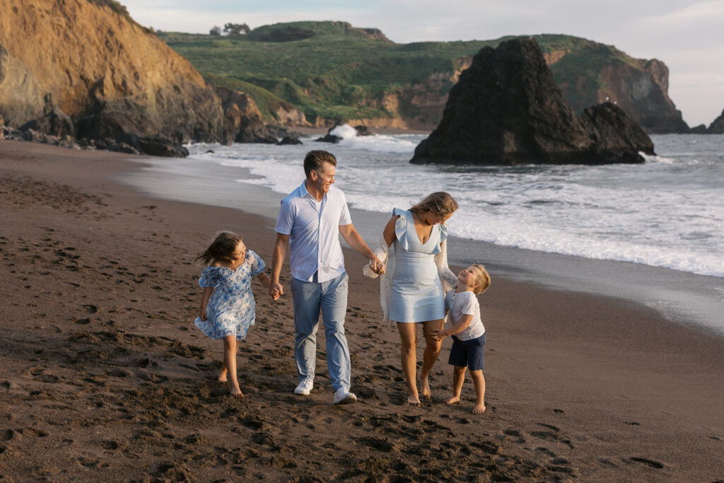 family of four walks along rodeo beach in marin county