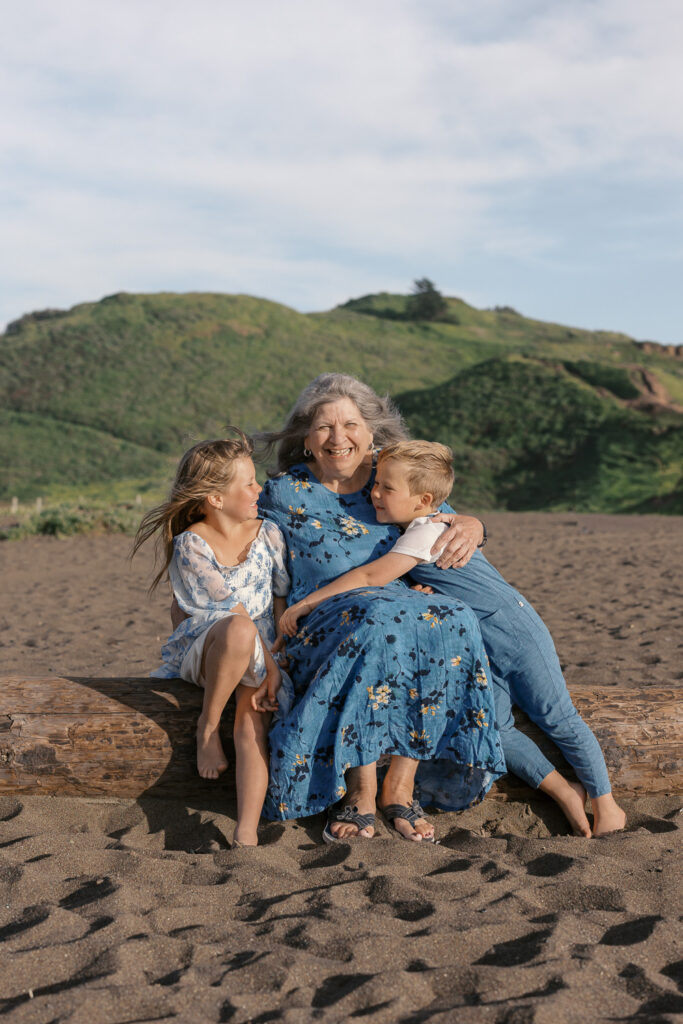two young children smile with grandma on rodeo beach
