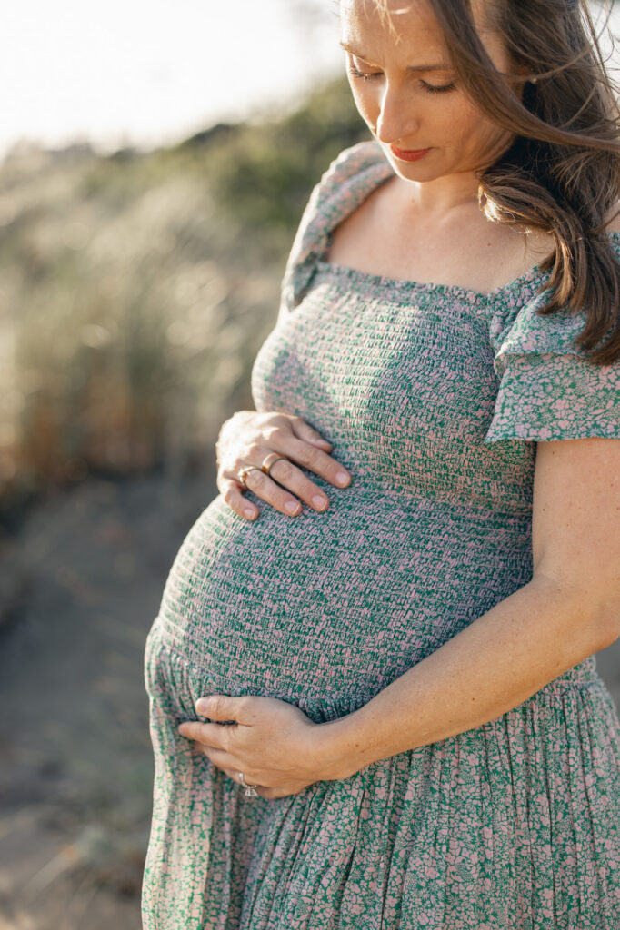Expecting mom gazes at her baby belly during an East Bay maternity photography session at Alameda Beach