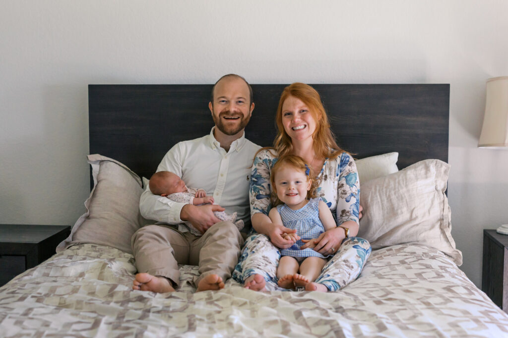 family of four smiles at the camera during an Alameda newborn photography session at home