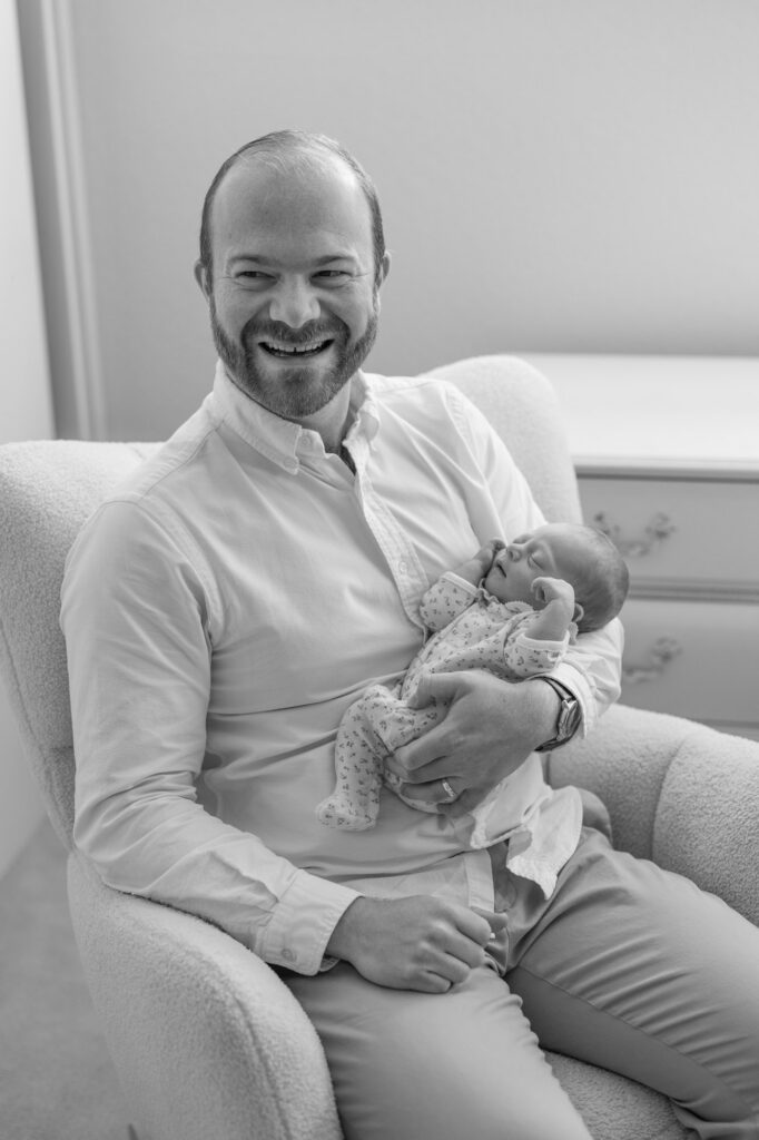 dad laughs while holding newborn baby daughter during Alameda newborn session