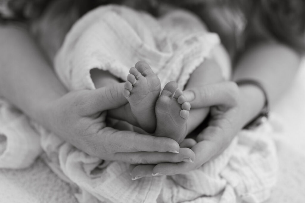 detail shot of newborn baby toes being held in moms hands during newborn photography session