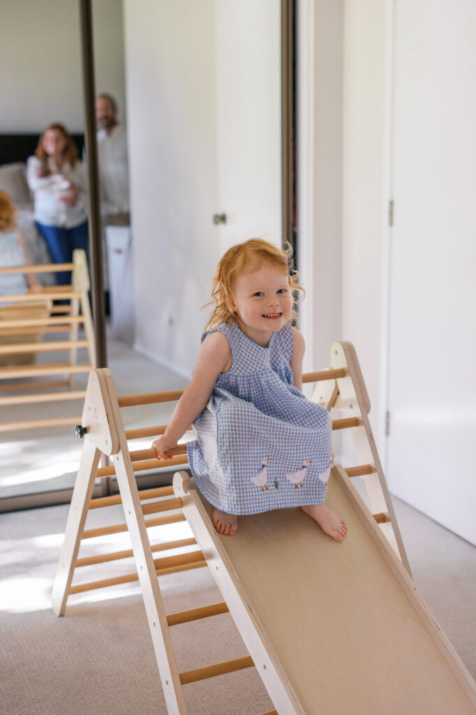 big sister toddler smiles as she plays during Alameda in home newborn session