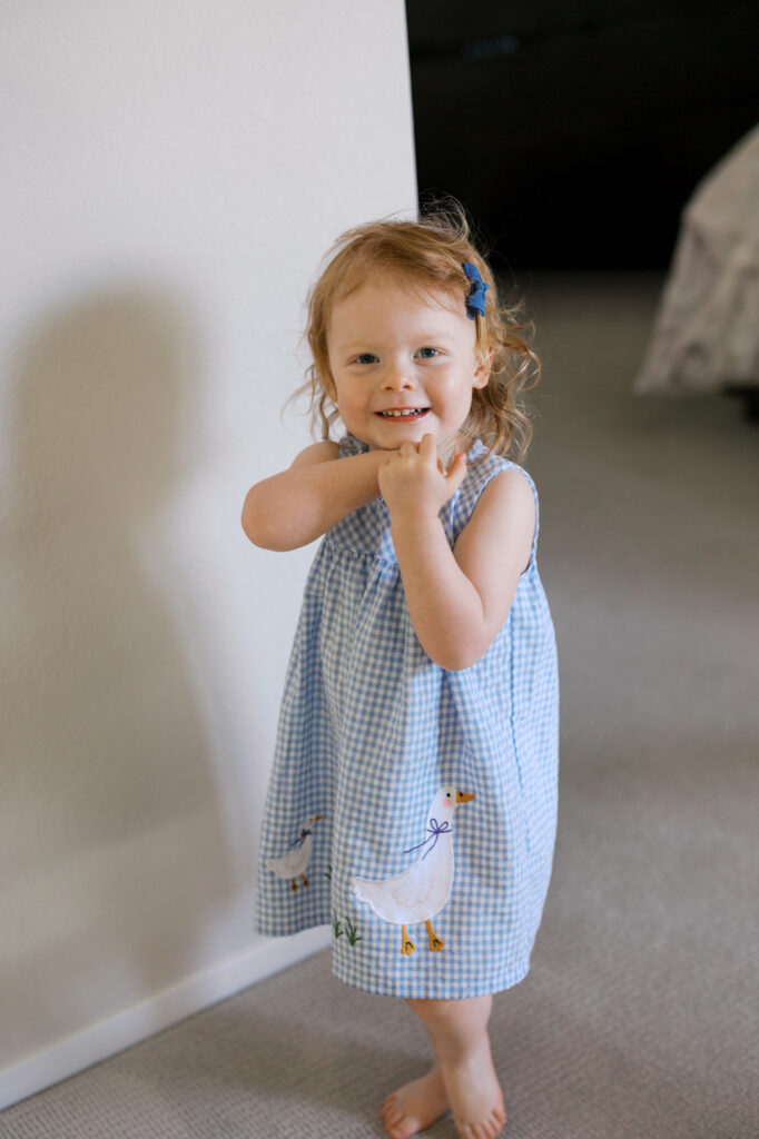 shy toddler smiles at newborn photographer during an Alameda session