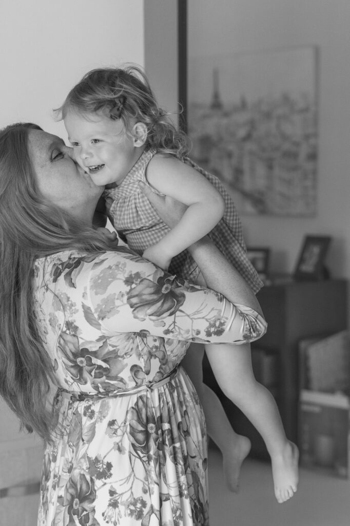 mom lifts toddler daughter who laughs happily during an in home Alameda photography session