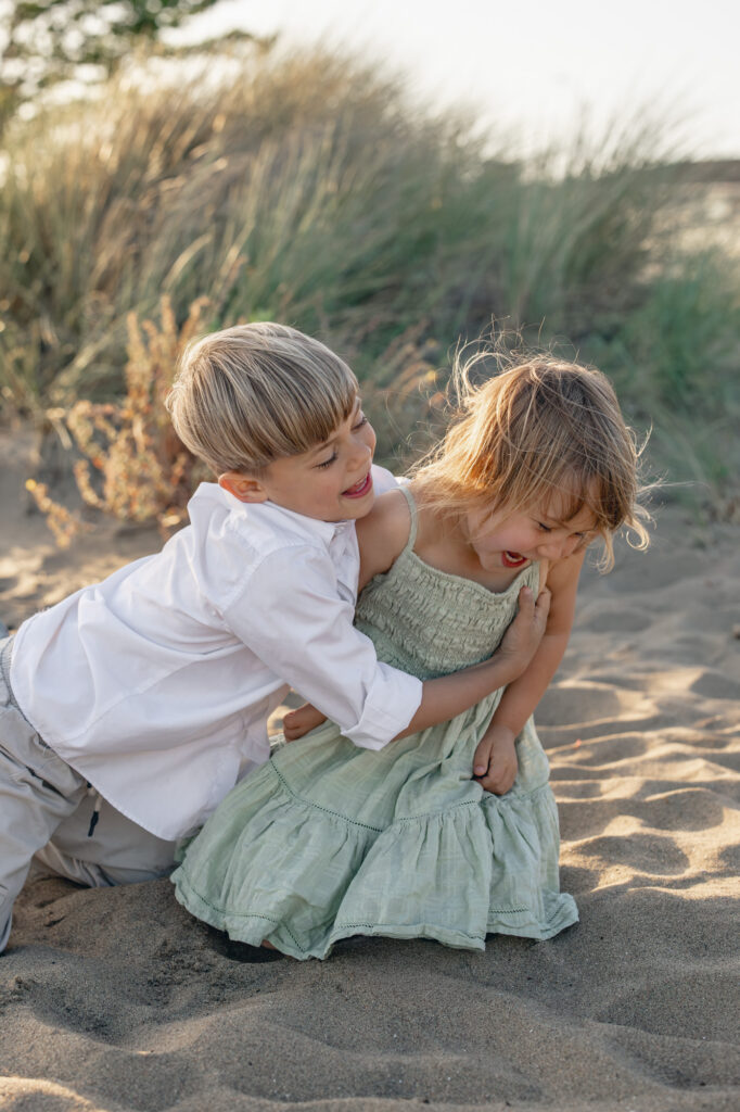 two young children play on Alameda Beach and laugh during an East Bay family photography session at golden hour