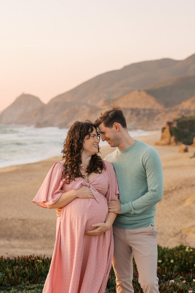 Expecting couple pose on the cliffs above the beach near Half Moon Bay for their Bay Area maternity photography photos