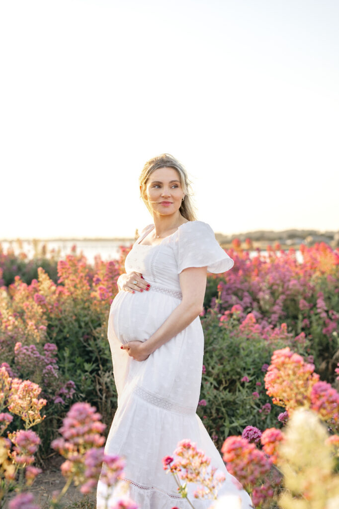 East Bay maternity photography with an expecting mother in a white dress standing in a field of pink flowers
