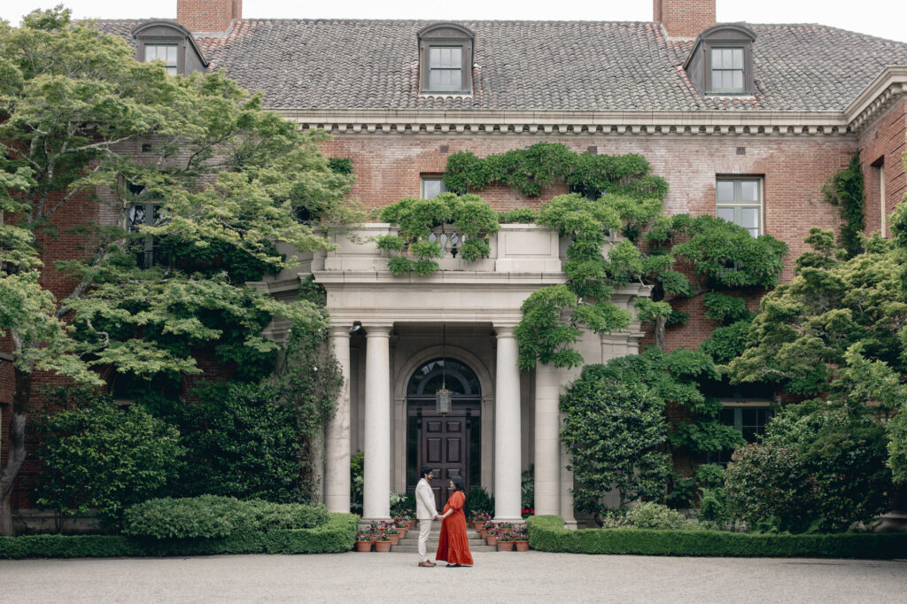 Expecting couple stand in front of Filoli's grand house in Woodside during spring for their Bay Area maternity photography session