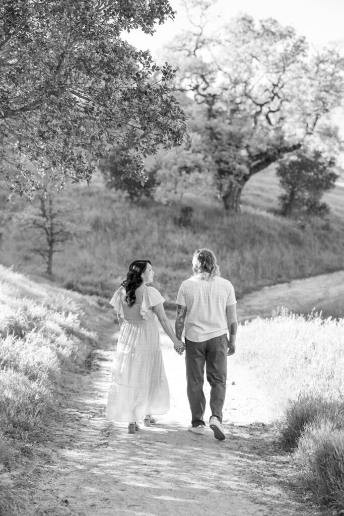 couple walk along a trail at Old Borges Ranch during their maternity photography session