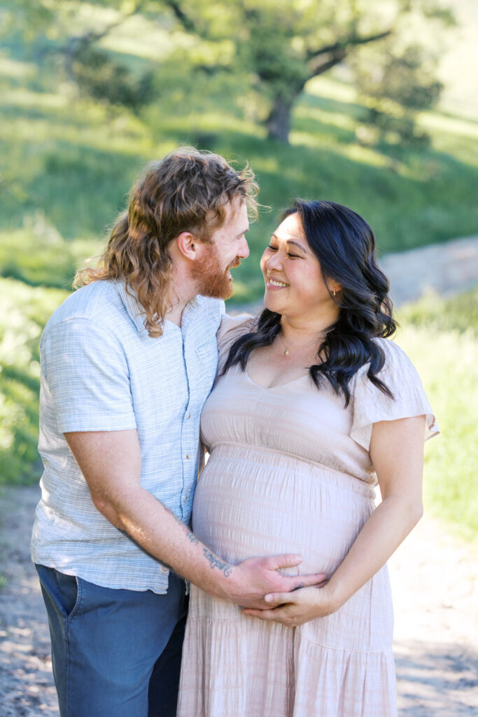 expecting couple laugh and gaze at each other during Walnut Creek maternity photography session