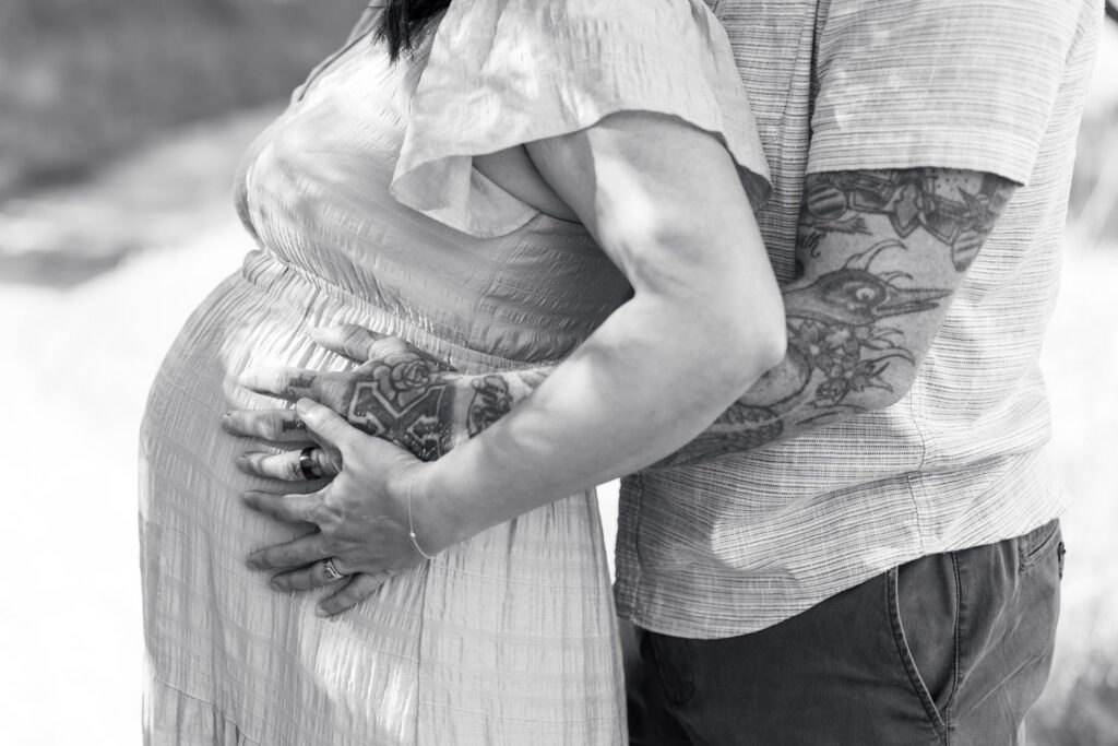 close up detail shot of a woman's baby bump and her and her husband's hands