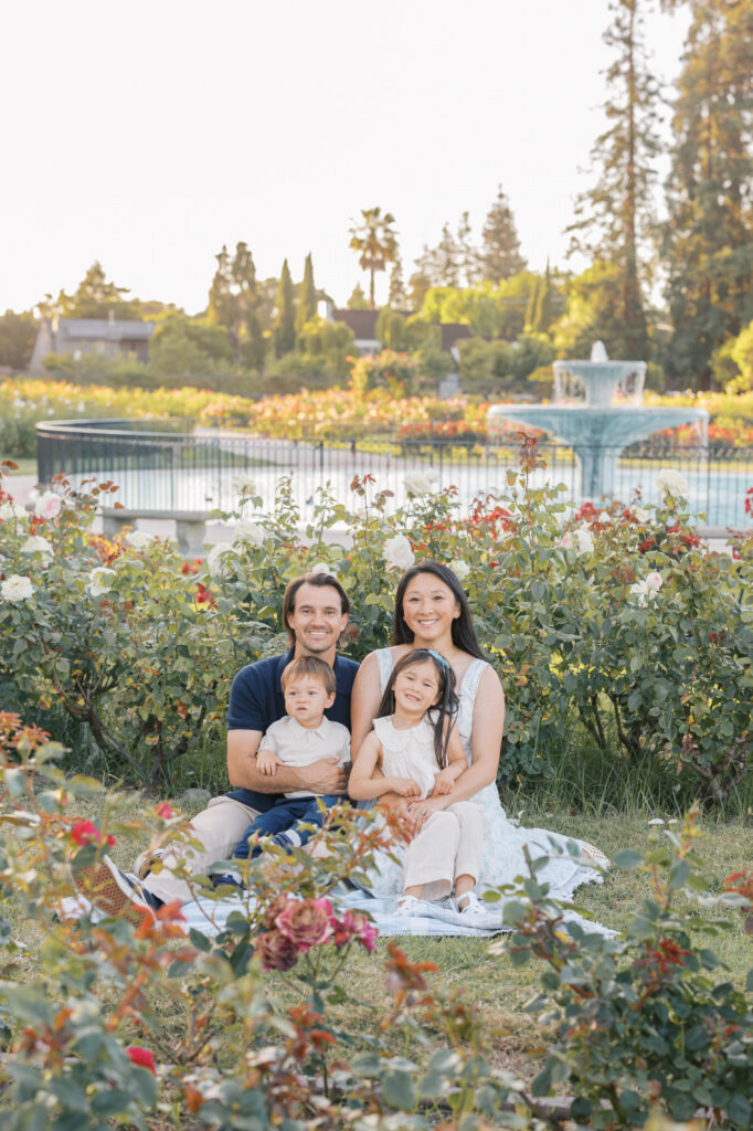 family of four sits on a blanket and poses during their San Jose Rose Garden family session