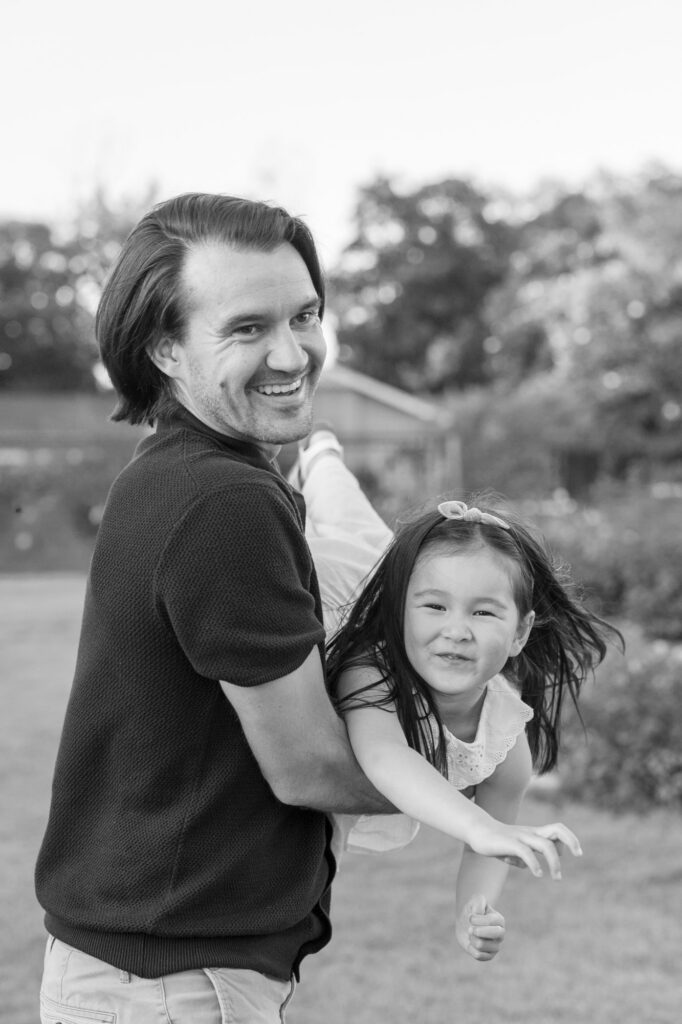 Fathers airplanes toddler daughter during San Jose Rose Garden photography session