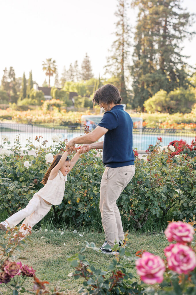 Father swings daughter thru the rows of roses at the San Jose Rose Garden