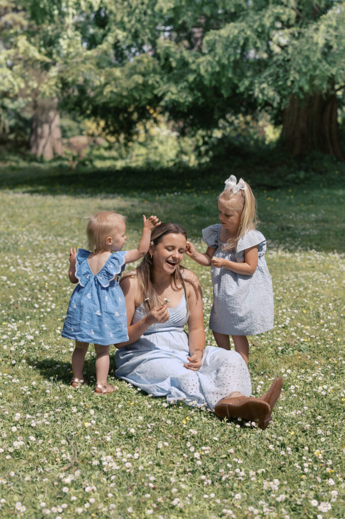 Two young girls put flowers in their mom's hair at Golden Gate Park during a family photography session