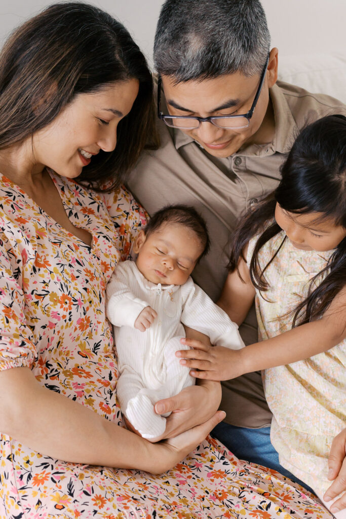 family of four all surround newborn baby boy at their home in San Mateo