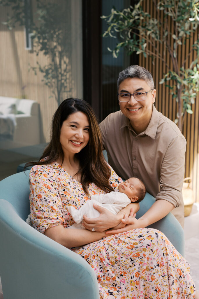 parents smile at the camera during their San Mateo newborn photography session while holding newborn baby boy
