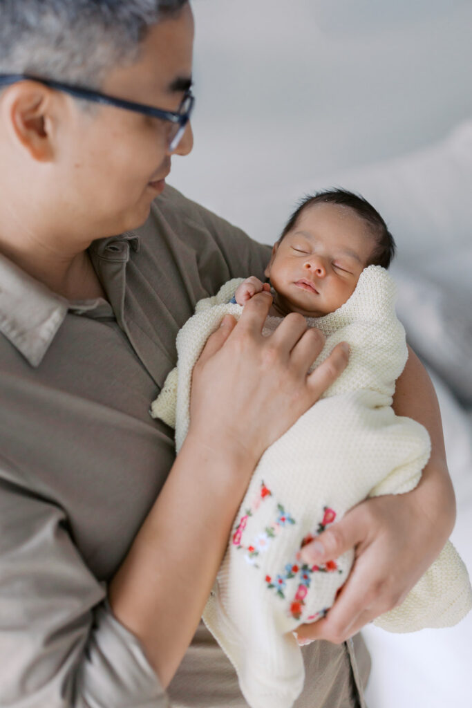 dad smiles down at his newborn baby boy during an in home session in San Mateo