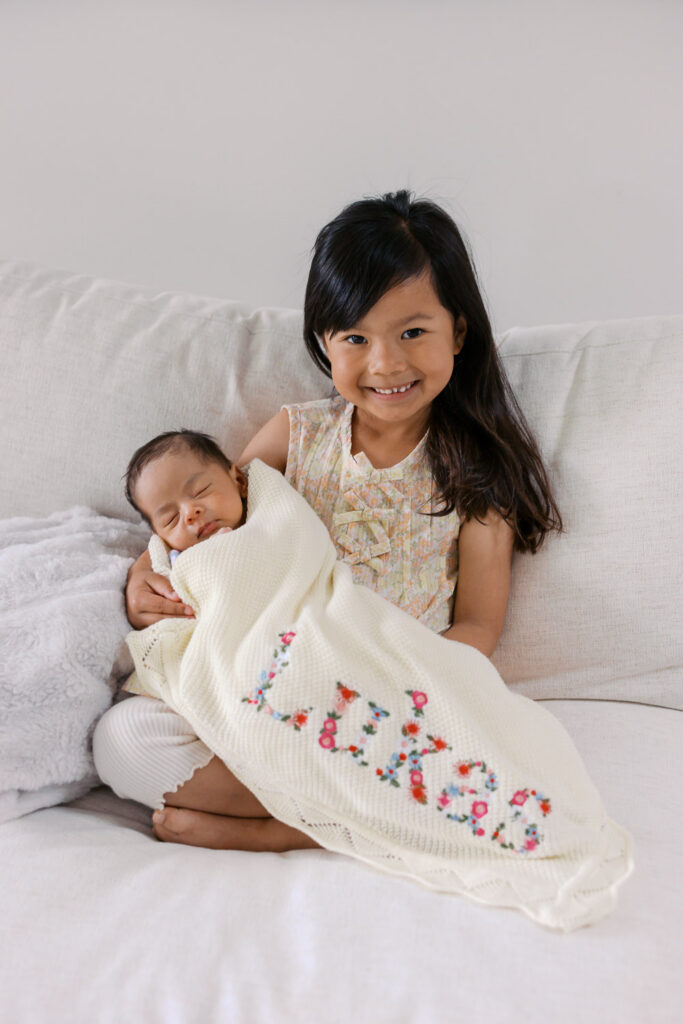 toddler girl and newborn baby brother pose for a sibling photo during their San Mateo newborn photography session
