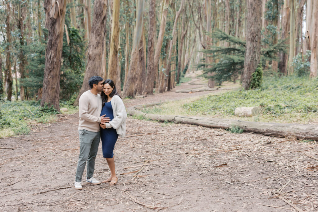 expecting parents embrace in the eucalyptus trees in Woodline in the Presidio during their San Francisco maternity photography session