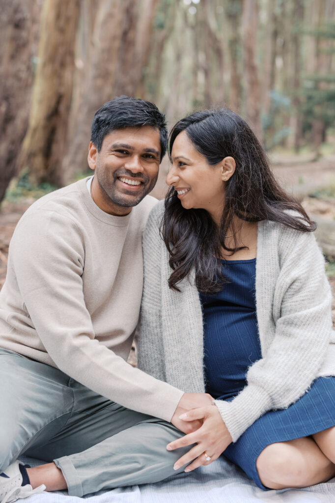 couple sit on a blanket in the Presidio during their maternity photography session
