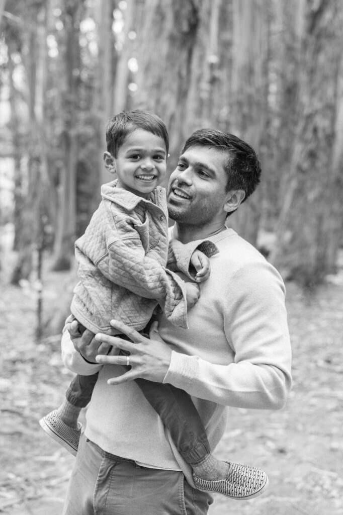 toddler grins at the camera while in Dad's arms