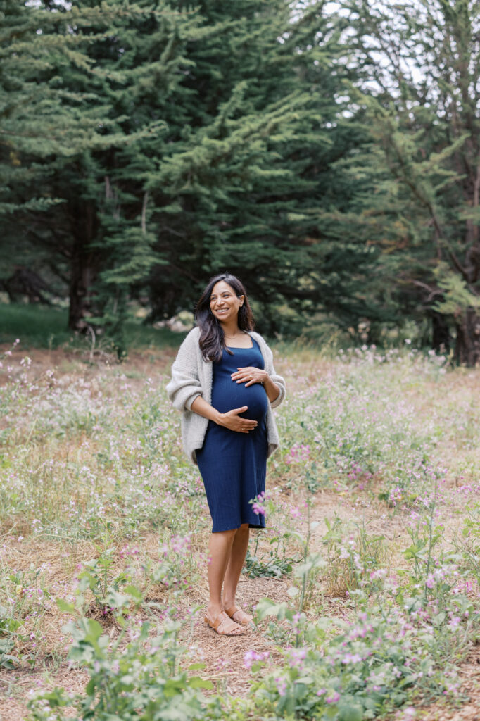 expecting mother in the wildflowers laughs at her family off camera during her San Francisco maternity photography session