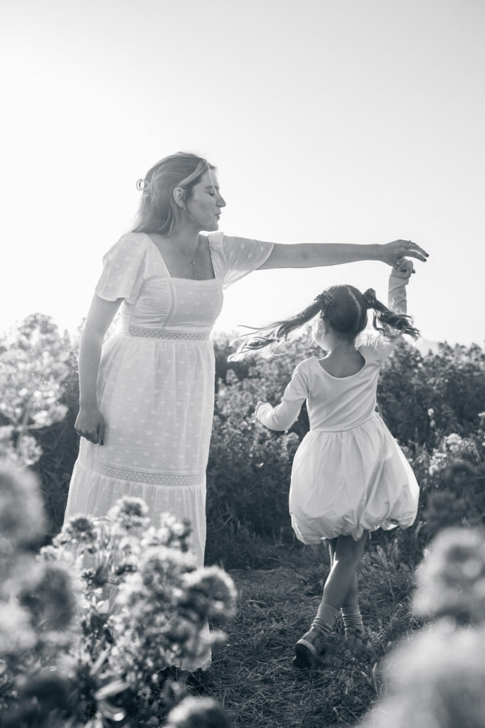 black and white image of mom and daughter dancing in flower fields during East Bay maternity session