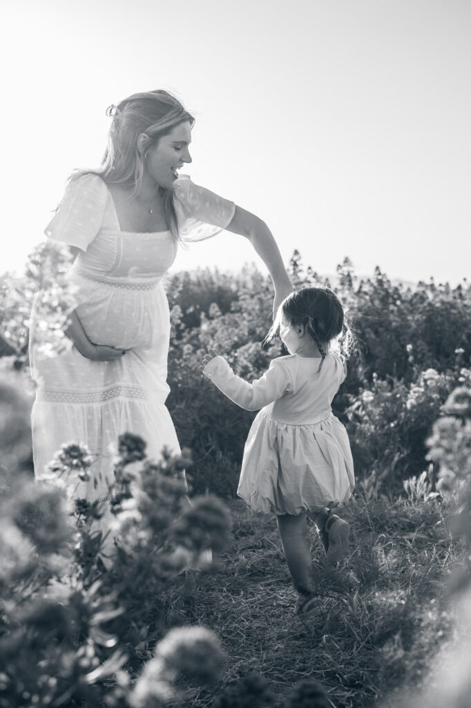 black and white image of mom and daughter dancing in flower fields during East Bay maternity session