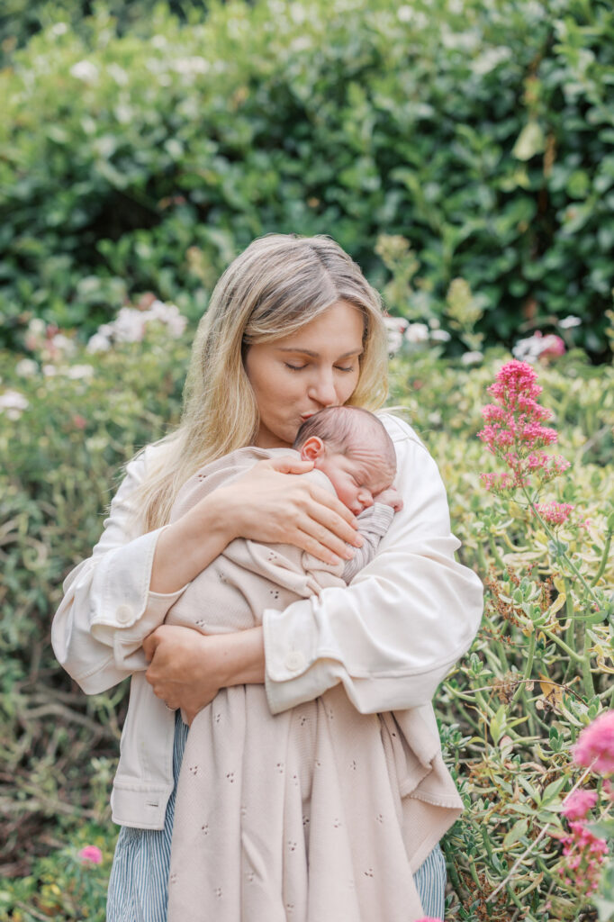 Mother kisses newborn baby boy's head in an East Bay quiet garden during her newborn session